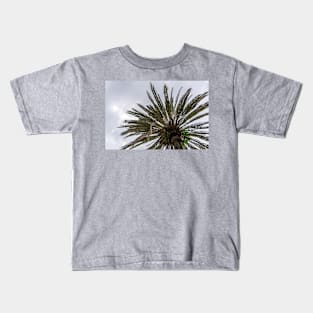 Palm tree silhouette against grey cloudy sky Kids T-Shirt